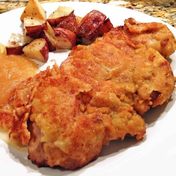 A plate of breaded pork with apple sauce.