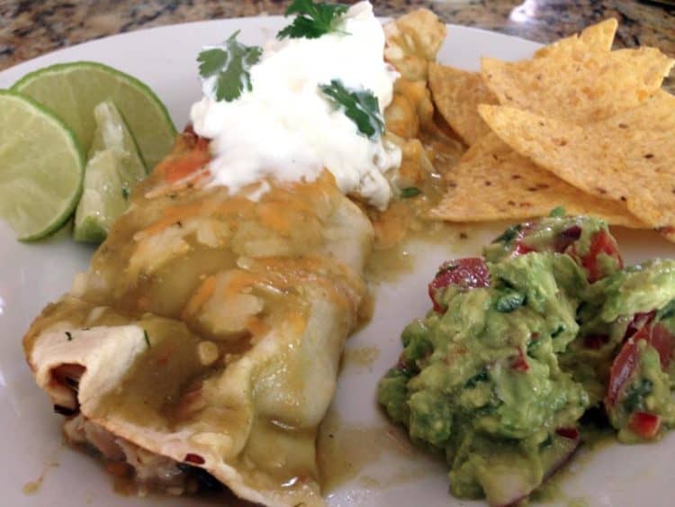 A close up of food on a plate, with Enchilada and Chicken