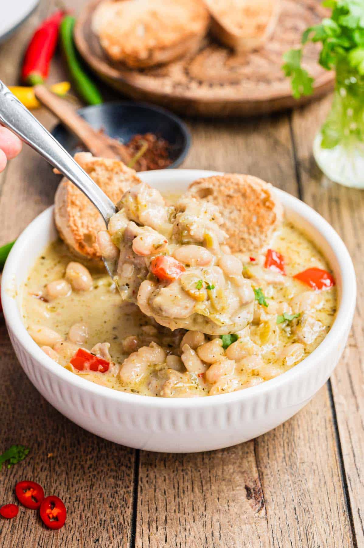 A bowl of white chicken chili and some bread.