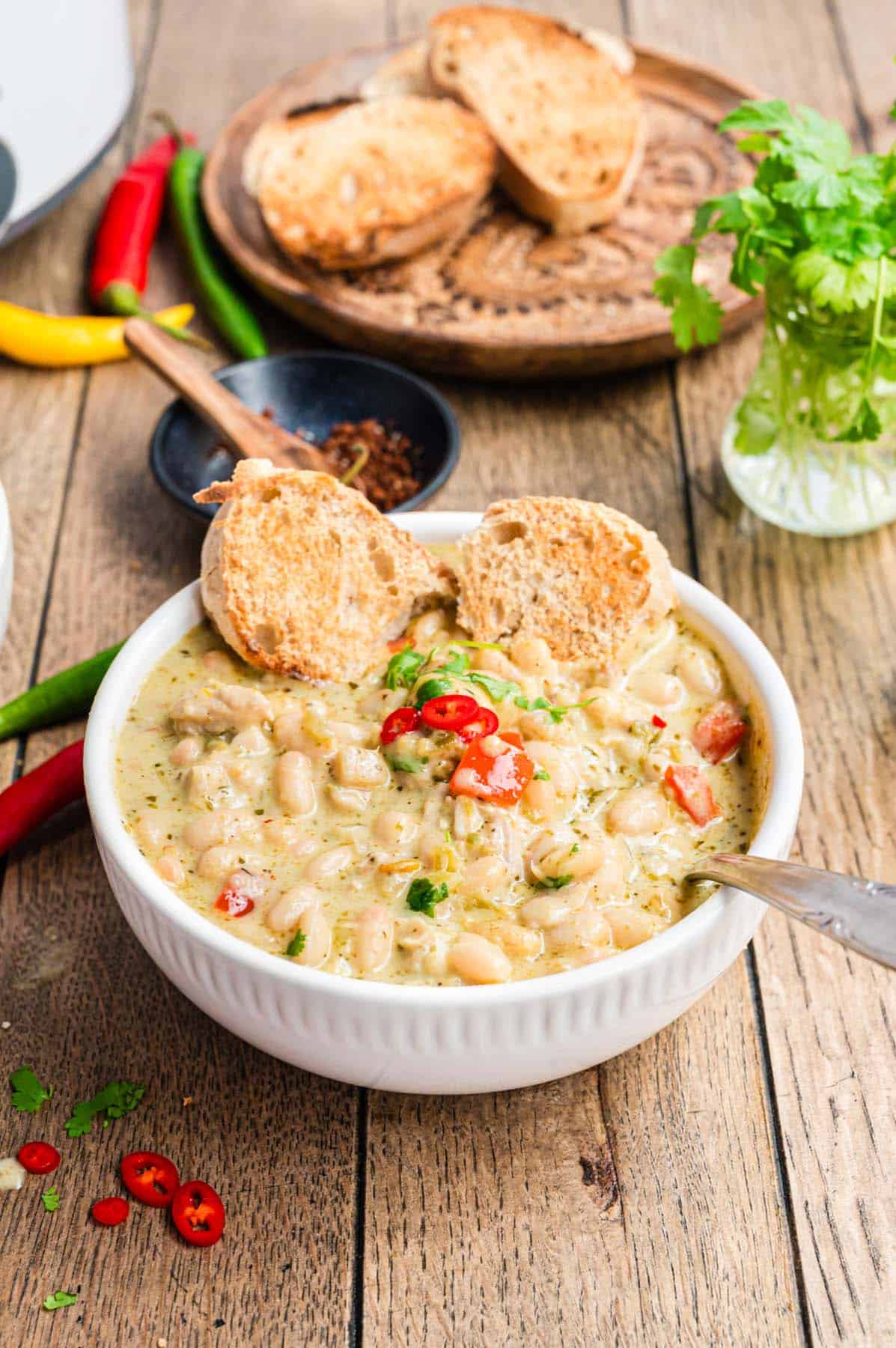 A bowl of white chicken chili with some rustic bread.