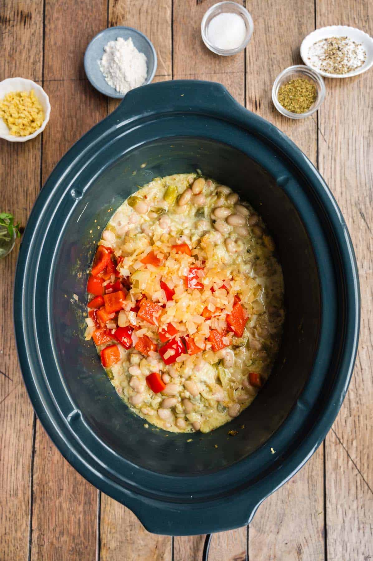 Some white beans and other ingredients in a crock pot.