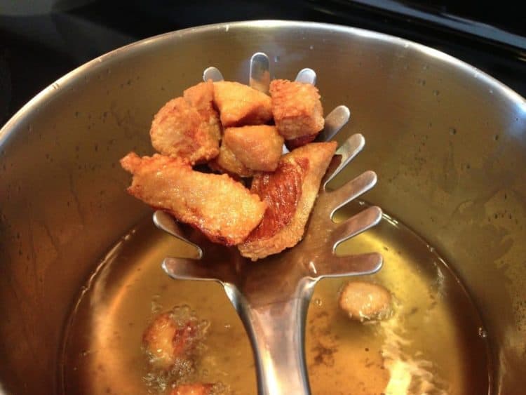 A pot of oil with polish sausage frying.