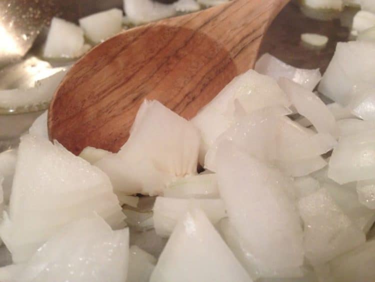 stirring onions in a pan with wooden spoon