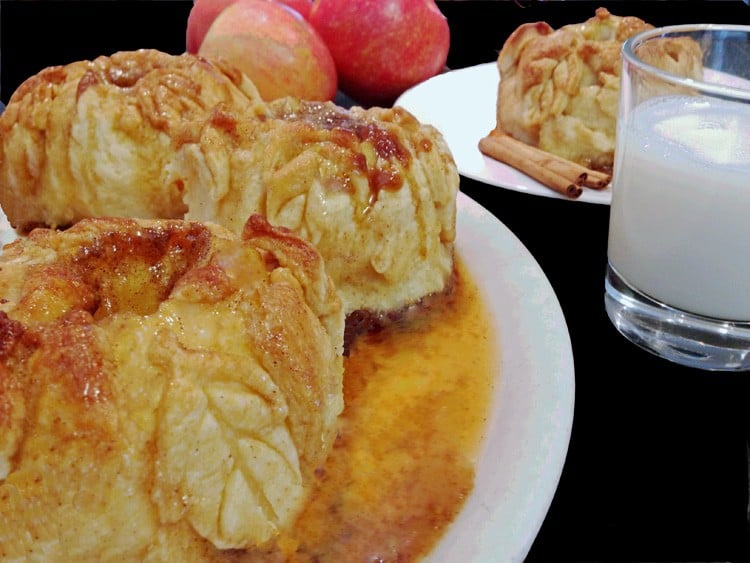 Plate of apple dumplings with homemade sauce and a glass of milk.