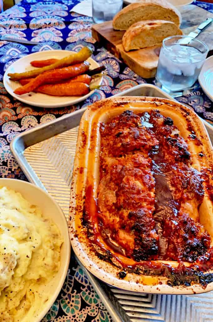 Pan of meatloaf with mashed potatoes, roasted carrots, and homemade bread.