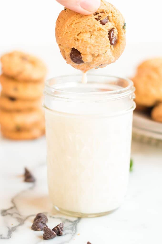 chocolate chip cookie being dunied into a glass of milk.