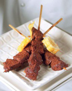 A plate of food with a fork, with Anticucho and Ají de gallina