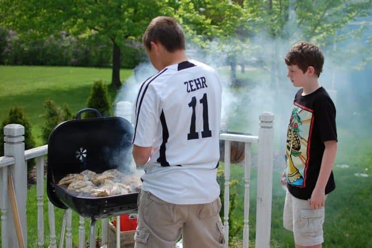 Two young men grilling chicken