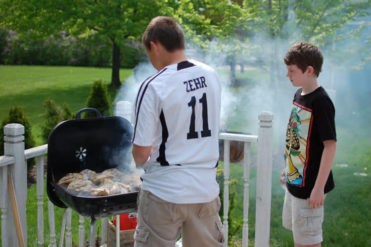 Two boys making Cornell barbeuce chicken Two young men grilling chicken