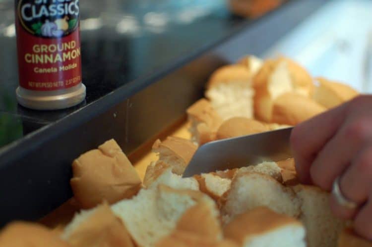 Cutting cubes of leftover bread into a baking pan