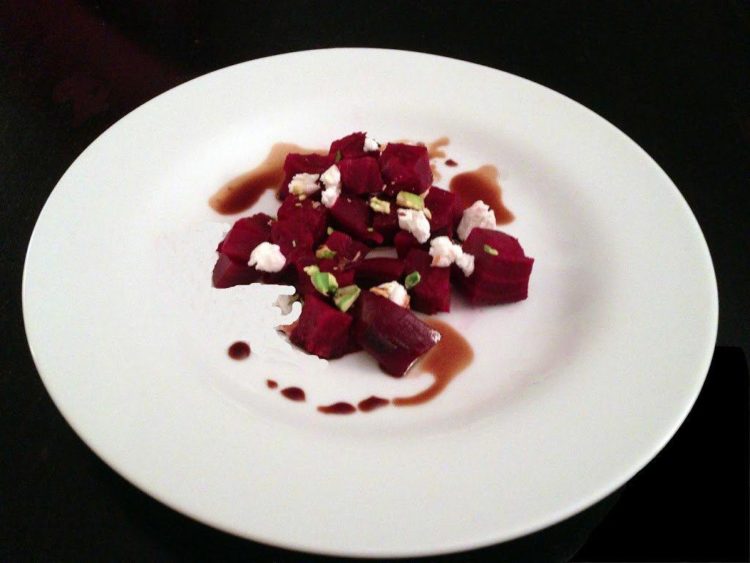 A plate of food on a table, with beet salad and goat cheese