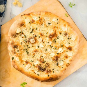 A garlic pizza on a cutting board.