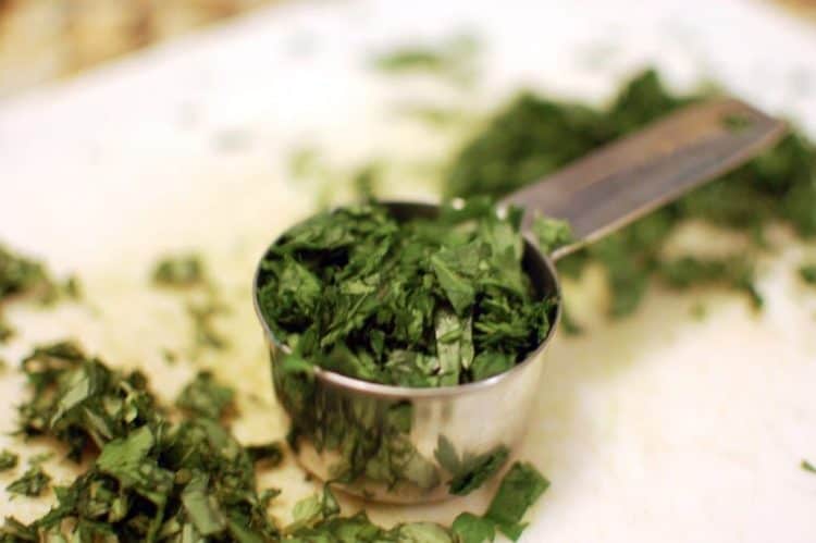 A measuring cup with chopped fresh herbs