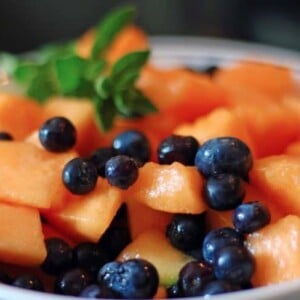 A bowl of fruit, with Cantaloupe and Berry