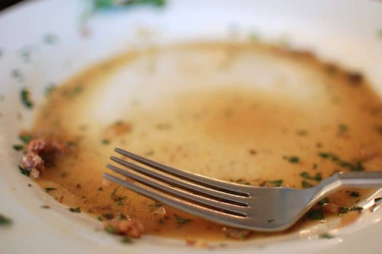 An empty plate with a fork and some sauce