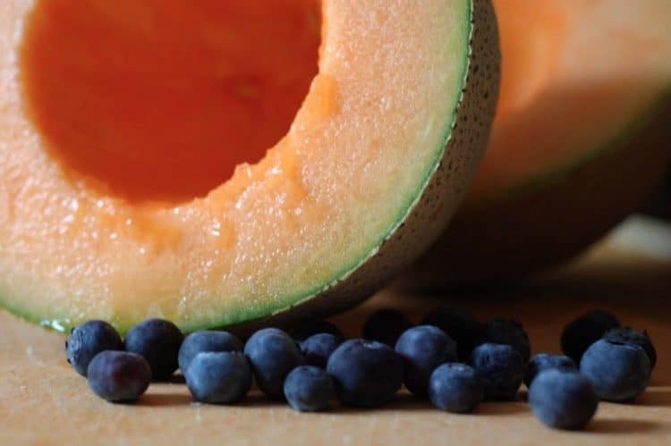 A close split cantaloupe and blueberries