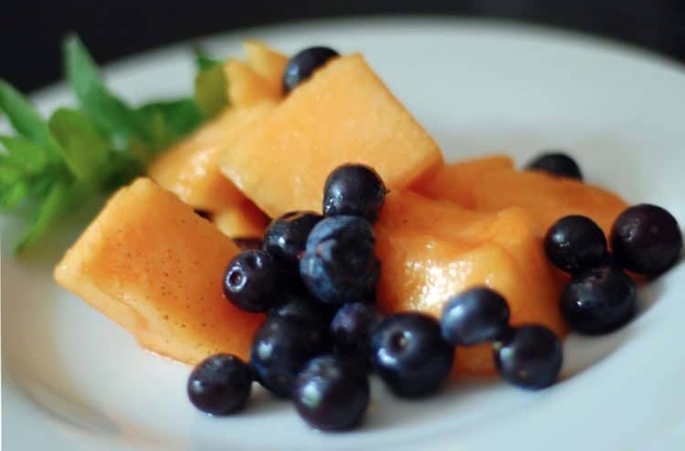 Diced cantaloupe and blueberries on plate with mint