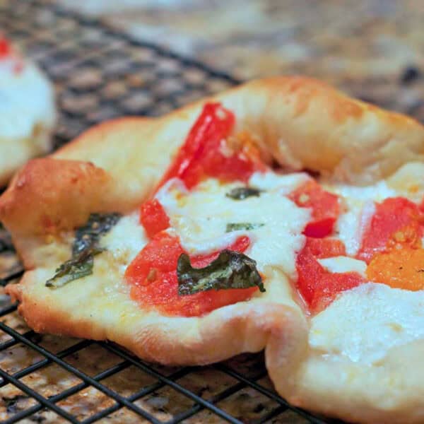 A personal size burrata margherita pizza on a cooling rack.