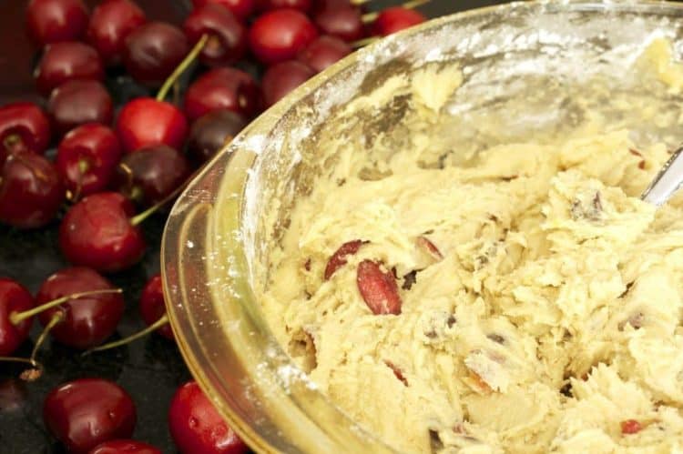A bowl of cookie batter with bing cherries