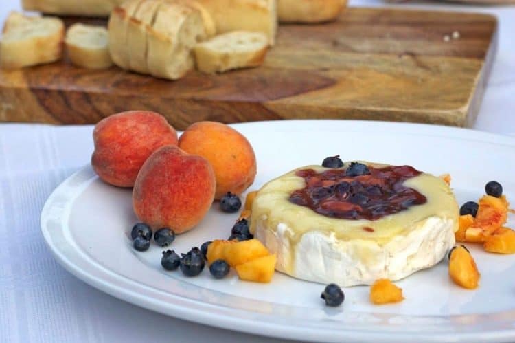 A plate of food on a table, with peaches and brie cheese