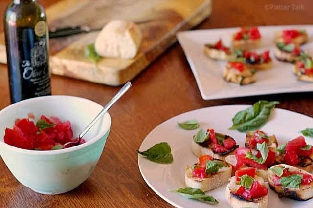 A bowl of food on a plate on a table, with Bruschetta and Tomato