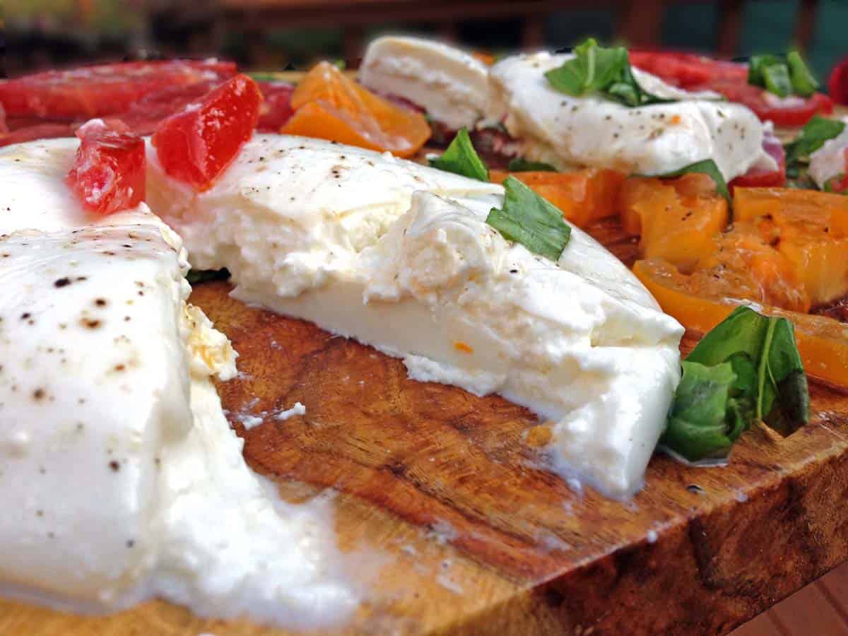 A round piece of creamy burrata cheese, with a wedge cut from it.