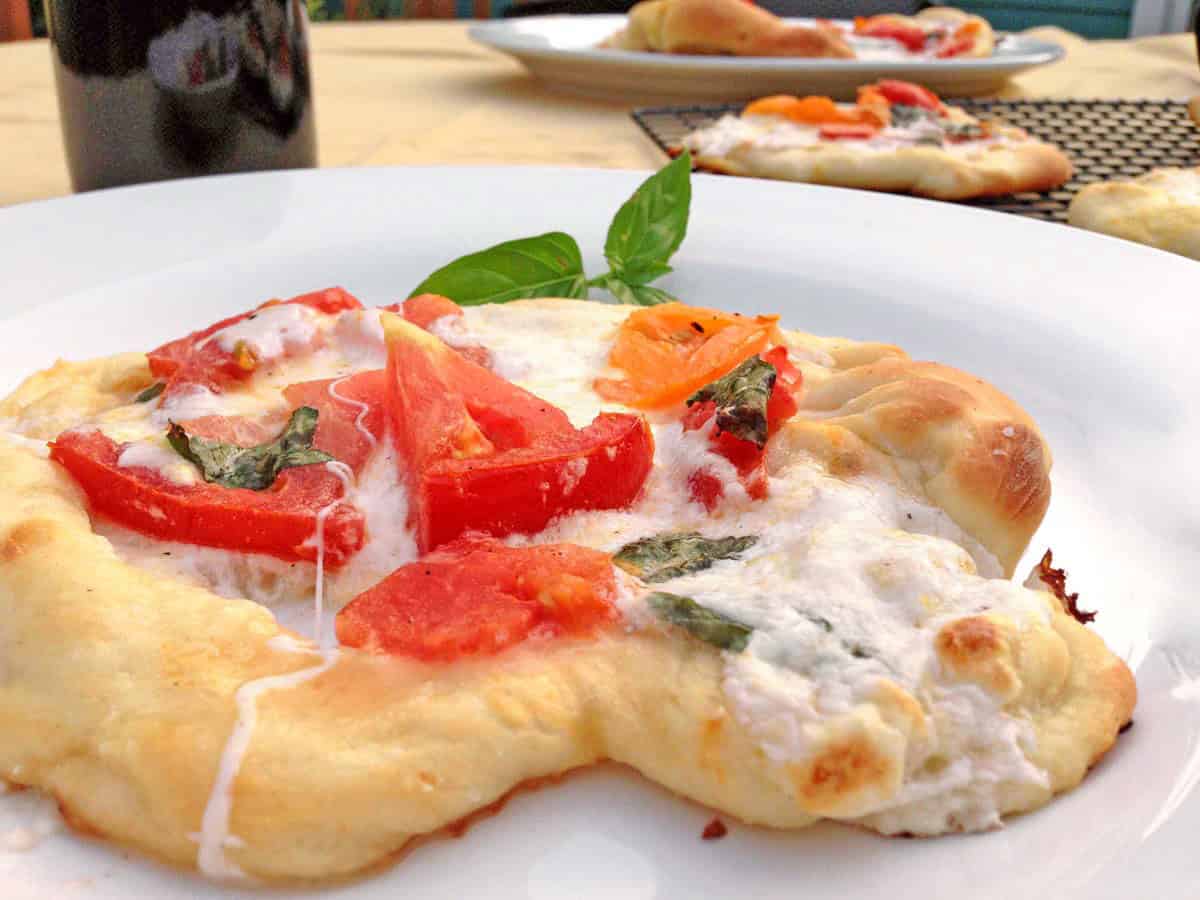 Slice of Burrata Margherita Pizza showing creamy melted burrata, fresh basil, and blistered tomato slices.