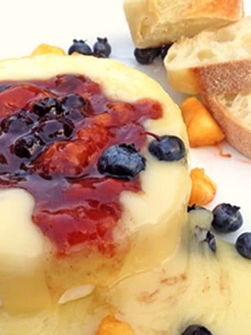 A hunk of baked brie with fruit and breaqd