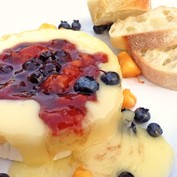 A hunk of baked brie with fruit and breaqd