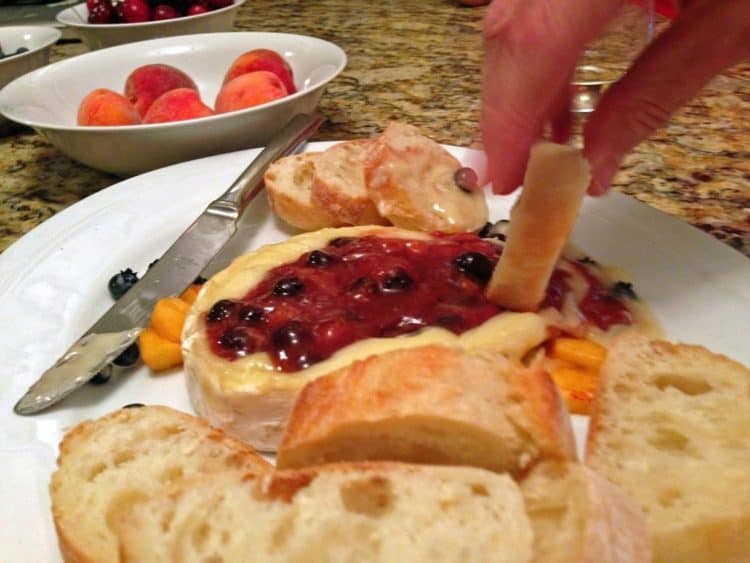 A person dipping bread into Brie