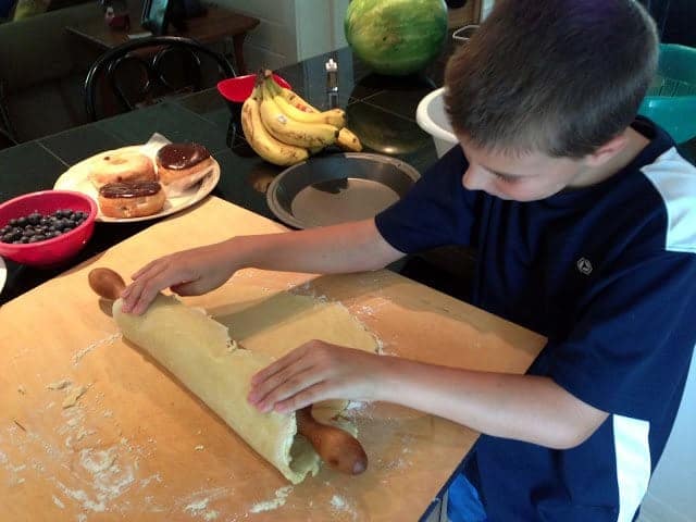 A boy rolling out a pie crust