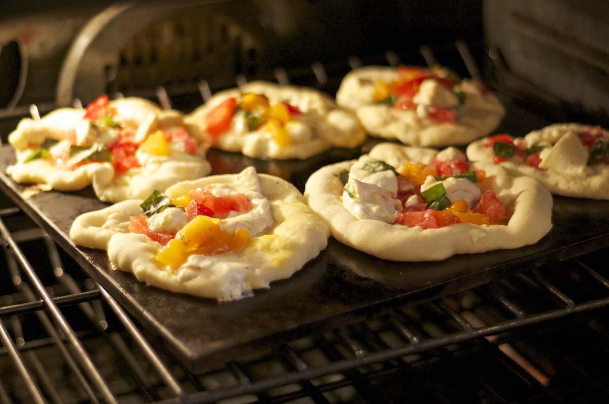 Some burrata Margherita Pizzas, baking in an oven.