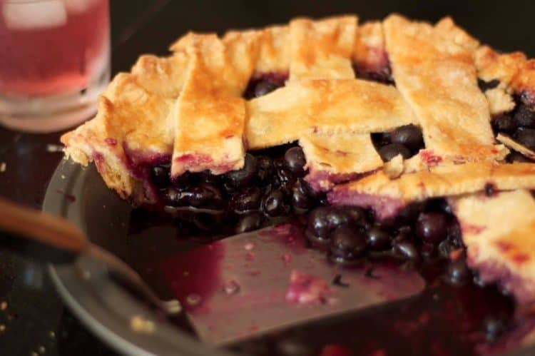 A close up of a plate of a cut blueberry pie