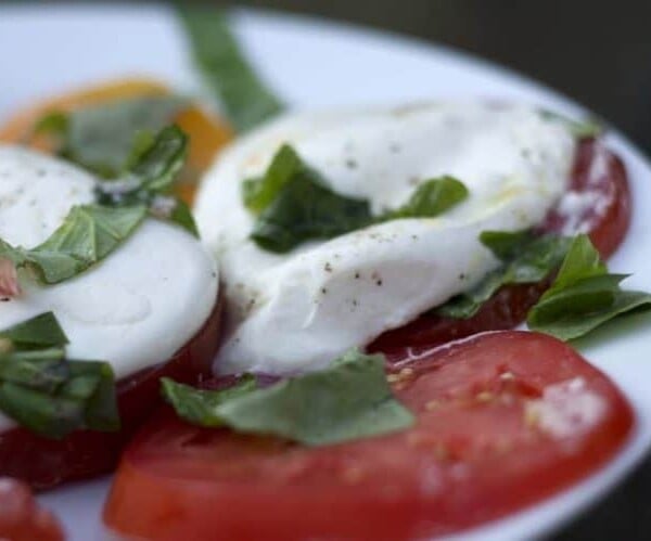 A plate of food, with Burrata and Caprese salad