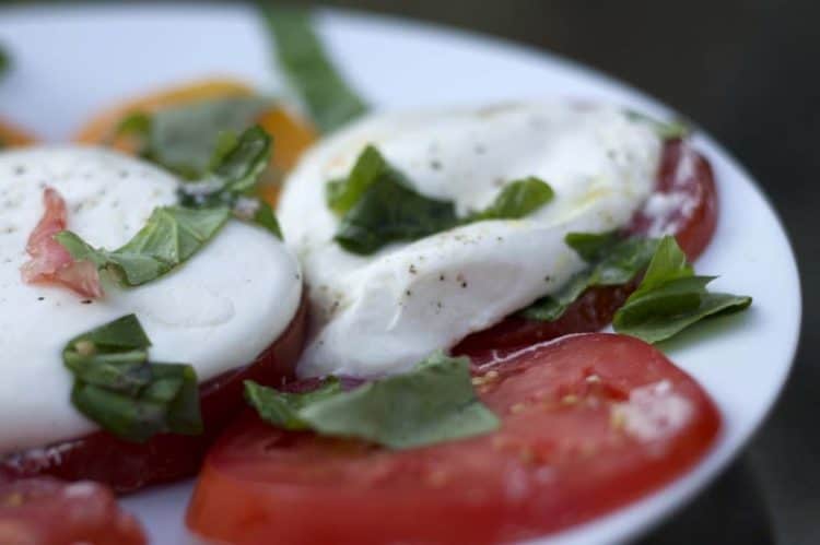 A plate of food, with Burrata and Caprese salad