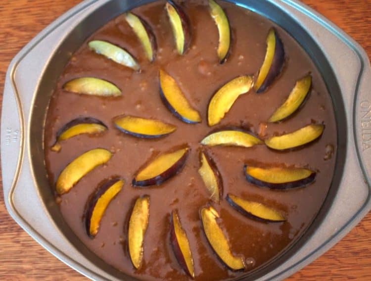 A pan full of cake batter and plums.