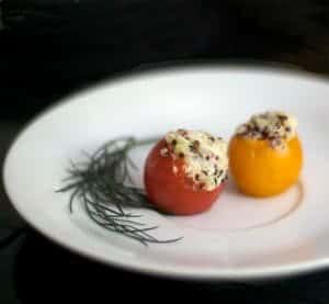 A plate of food with two stuffed tomatoes.