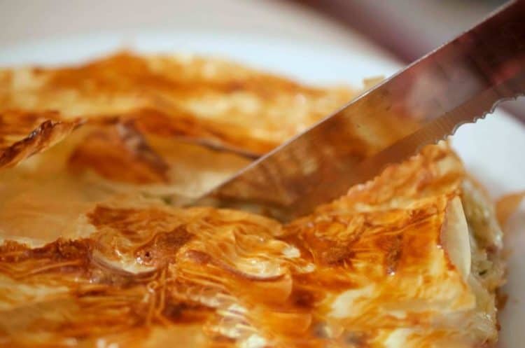 A close up of a Italian pie being cut. 
