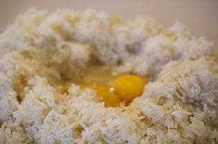 A close up of shredded potatoes and an egg.