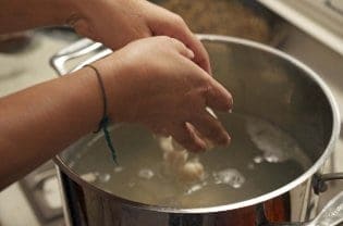 Gnocchi getting put into water in a pot.