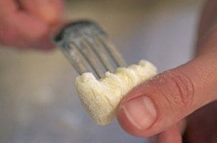 A close up of a fork forming gnocchi.