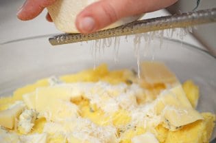 Shaving cheese into a bowl of food.