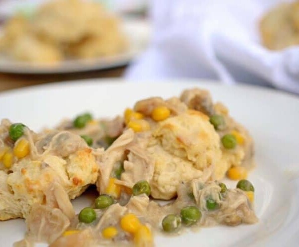 A close up of a plate chicken and biscuits.