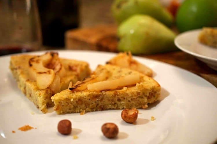 A slice of cake with hazelnuts and pears.