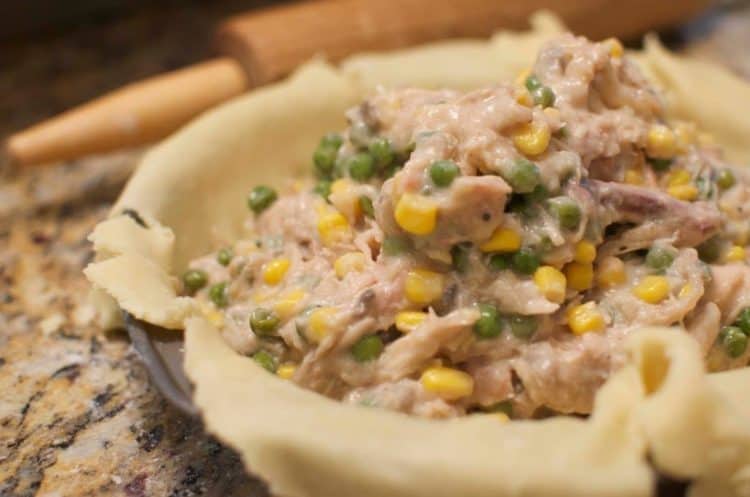 A close up of a pot pie being assembled.