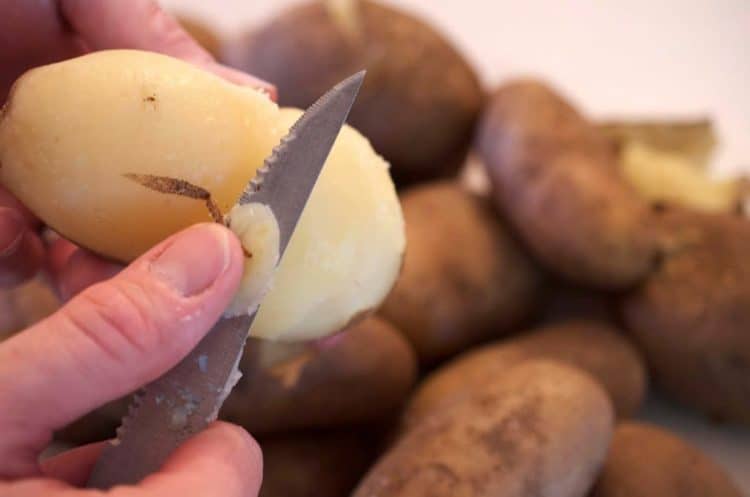 A close up of a potato being pealed.