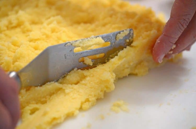 Someone cutting a piece of polenta.