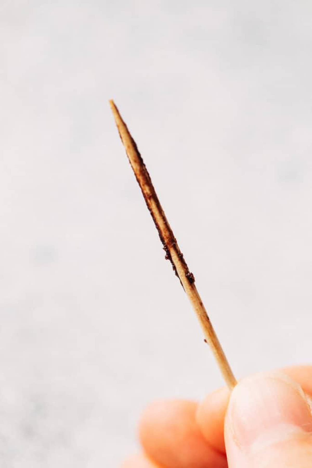 A toothpick with some brownie crumbs and batter on it.