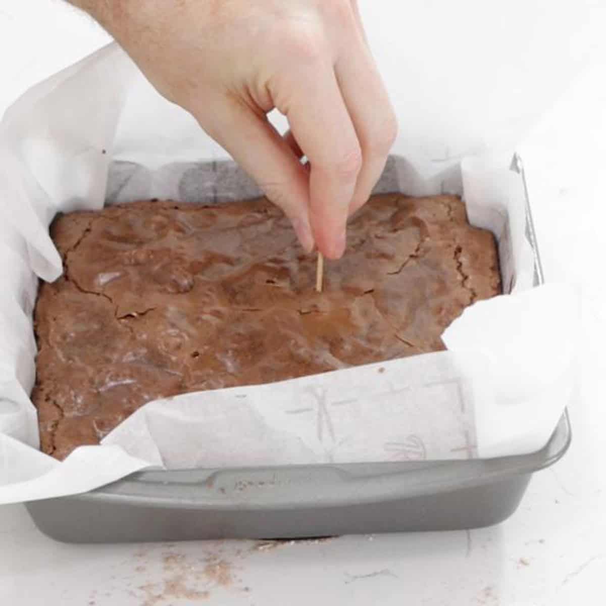Sticking a toothpick into a pan of brownies.