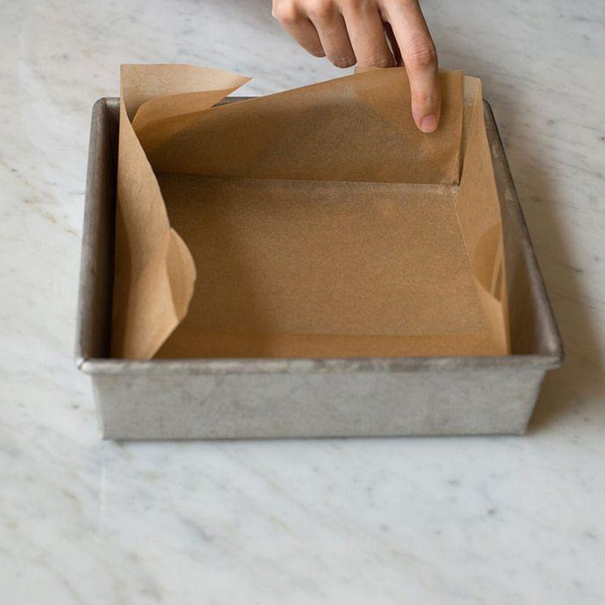Lining a baking pan with parchment paper.